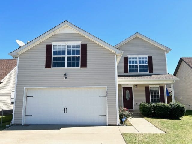 A two-story suburban house with a front-facing garage and a blue sky background.