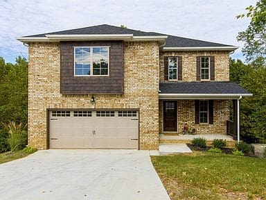 New two-story brick house with attached garage and concrete driveway.