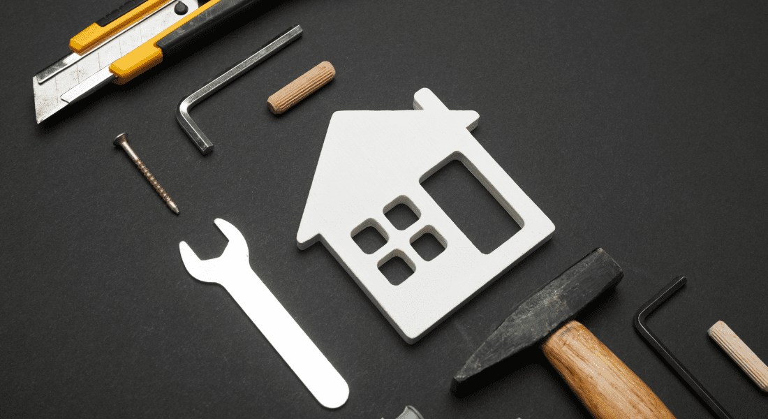 Assorted hand tools and a house silhouette on a black background, symbolizing home improvement or construction.