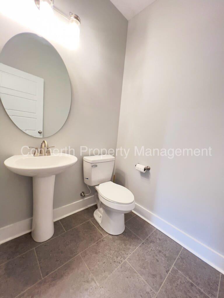 Toilet with white sink and white cammod and oval mirror on wall