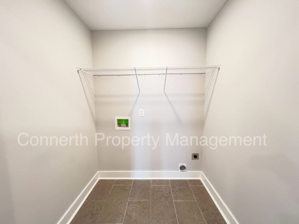 An empty laundry room featuring a tiled floor, a wire shelf above wall-mounted connections, and labeled with 