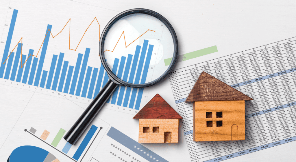 Magnifying glass over bar and line graphs, next to small wooden house models. Spreadsheet in the background. Financial analysis and real estate concept.