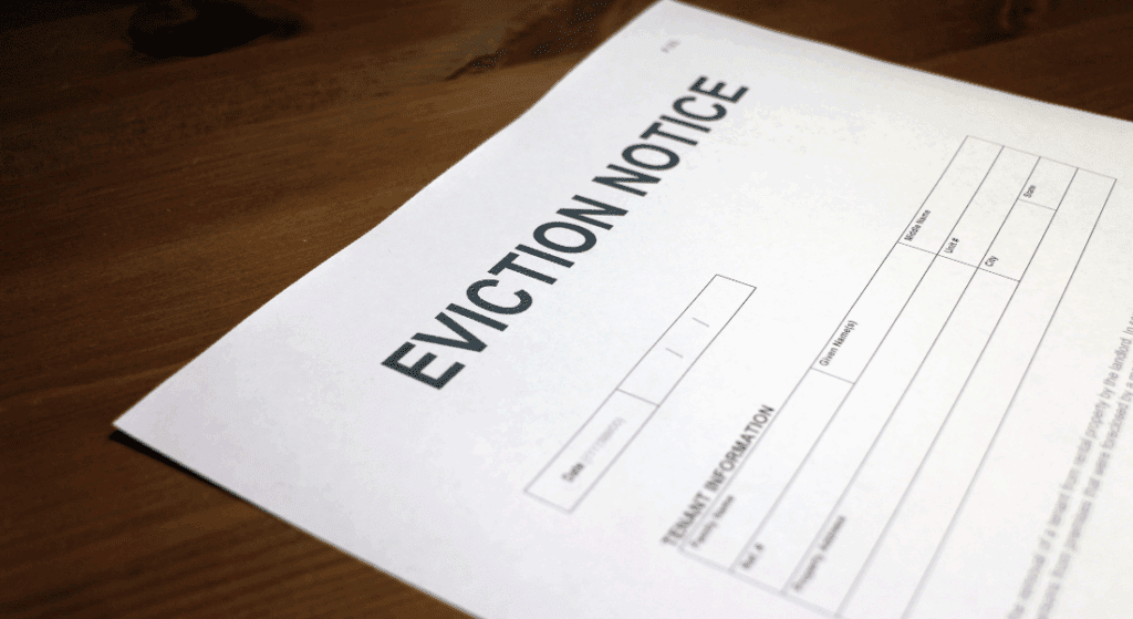 A close-up of a paper document titled "Eviction Notice" laying on a wooden surface, with blank fields for tenant information.